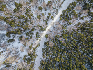 Flight over the winter mountains with road serpentine and pine forest. Top down view. Landscape photography