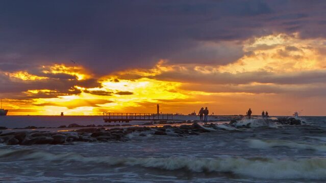 Sunset time-lapse on pier with people walking and ships passing. by.