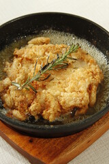 Tuscan style chicken sizzling in butter with rosemary in a skillet