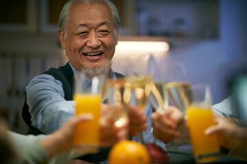 elderly asian man having a toast during dinner at family gathering