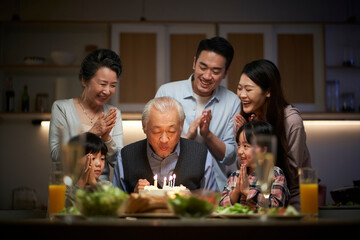three generation asian family celebrating grandpa's birthday at home