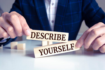 Closeup on businessman holding a wooden block with DESCRIBE YOURSELF message