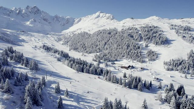 Ski track with skiers descending with lift left at Courchevel France, Aerial pan left reveal shot