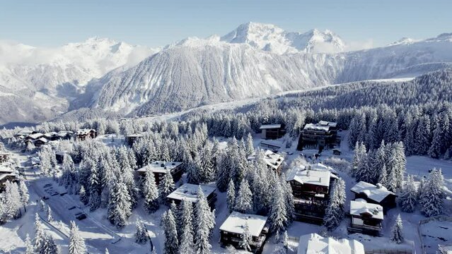 Ski resort with cabin chalets in the Alpine mountains at Courchevel France, Aerial pan left shot