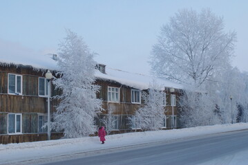 A girl walks down a snowy street on a frosty day. Western Siberia. Russia