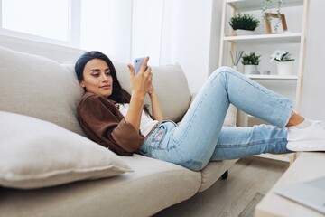 Woman blogger with phone lies at home on the couch and works freelancer online, selfie