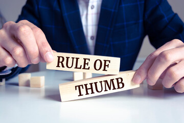 Closeup on businessman holding a wooden block with RULE OF THUMB message, business concept