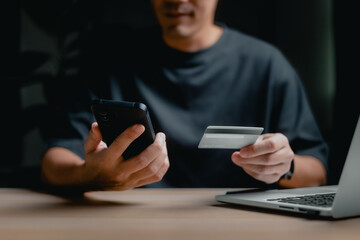 online shopping and E-commerce concept, happy smile Man hand using smartphone and holding credit card for shopping payment online at home.