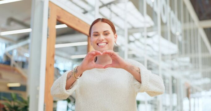 Woman in office walking with heart sign, hands and smile, happy corporate leadership in creative startup company. Happiness, business and love hand gesture, happy woman management at design agency.