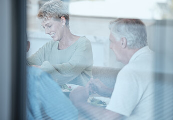 Obraz premium Love, celebration and family with dinner through window enjoy festive meal, lunch and eating food together. Christmas, thanksgiving and grandparents bonding, happy and laugh at dinner party at home