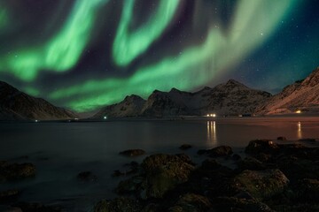 Fototapeta na wymiar Aurora borealis with stars over mountain range on coastline