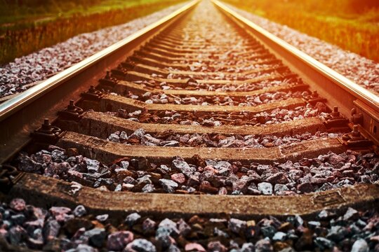 Railway track line in sunlight, railroad train track landscape with ballast gravel and crushed stone
