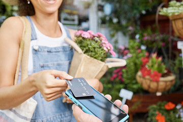 Customer, shopping and credit card for florist shop payment with POS machine or phone for sale of flowers at small business. Hands of woman paying with rfid technology for service at retail store