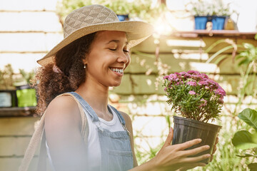 Woman, smile and flower pot plant while shopping at florist shop for buying gardening plants at a nursery and garden store. Black female or happy customer with flowers for sale in a greenhouse