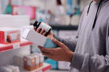 Customer looking at pills bottle and vitamins box, wanting to buy medicinal product for healthcare treatment. Person checking packages of medicaments before buying drugs. Close up.