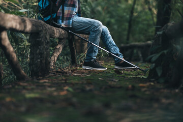 Naklejka premium hiker with backpack sitting on old wood fence in the forest while a rest. hiking and adventure concept.
