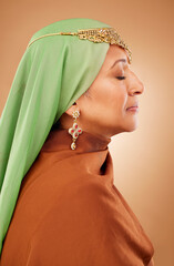 Muslim, culture clothes and senior woman with jewelry, faith and hijab against a brown studio background. Islamic fashion, traditional and modest burka model with religion, spiritual and scarf