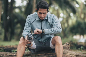 sport man checking at smartwatch during training and running in the park. Outdoor workout,  Healthy...
