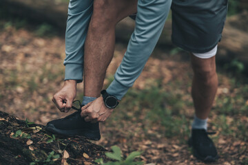 Sport man  tying jogging shoes in the forest. Outdoor workout,  Healthy lifestyle concept.