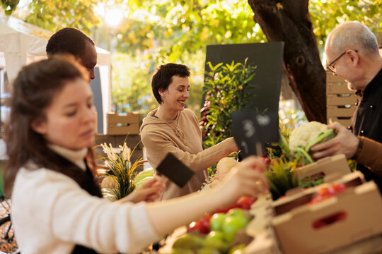 Young Happy Cheerful Woman Enjoying Shopping Experience At Local Farm Market, Female Customer Standing At Fresh Organic Produce Stand And Buying Healthy Locally-grown Products