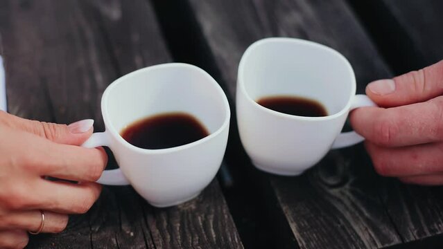 Close-up of lovers' hands with cups of coffee. Lovers are treated to drinks