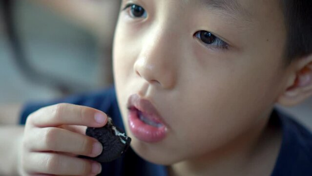 Close up Asian kid hand carry and eat cookies OREO.