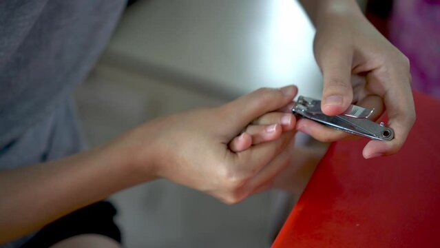 Close up mother use nail clipper cut the long nail of daughter