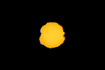 Torn black hole on yellow paper background. As template for text or advertisement.