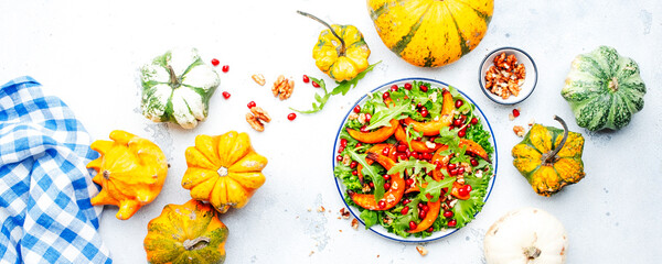 Fresh pumpkin salad with baked sweet pumpkin, lettuce, arugula, pomegranate and nuts. Healthy vegan comfort food. White background. Top view banner