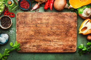 Food background. Rustic wooden cutting board. Vegetables, mushrooms, roots, spices - ingredients for vegan, cooking. Healthy eating, diet, comfort slow food. concept. Old kitchen table, top view