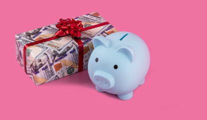 Blue piggy bank and gift box depicting 100 american dollar bills on a pink background