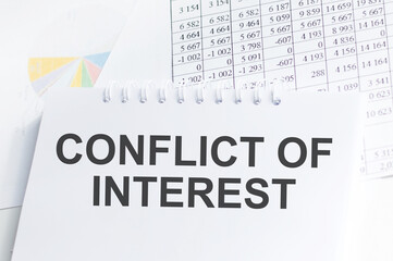 CONFLICT OF INTEREST text on sticky on black notebook