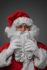 Portrait of christmas santa claus with glasses stroking his beard looking at camera.