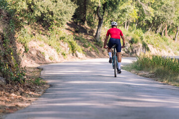 rear view of a cyclist riding relaxed with his mountain bike on a forest road, concept of freedom and sport in nature