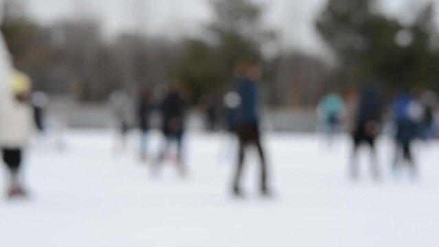 People skating on an ice skating rink on a winter day. Blurred background. Leisure entertainment vacation weekend holidays winter activities lifestyle. Public city winter fun ecreation enjoying.