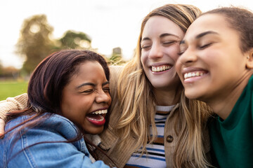 Closeup portrait of three authentic united multi-ethnic best women friends hugging each other outdoors. Diversity and unity concept