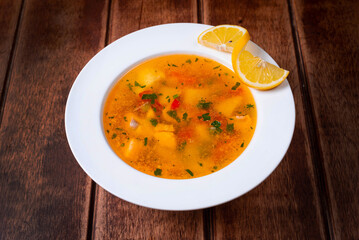 soup with fish and lemon on a wooden background