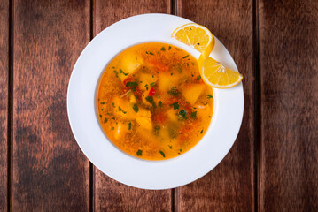 soup with fish and lemon on a wooden background