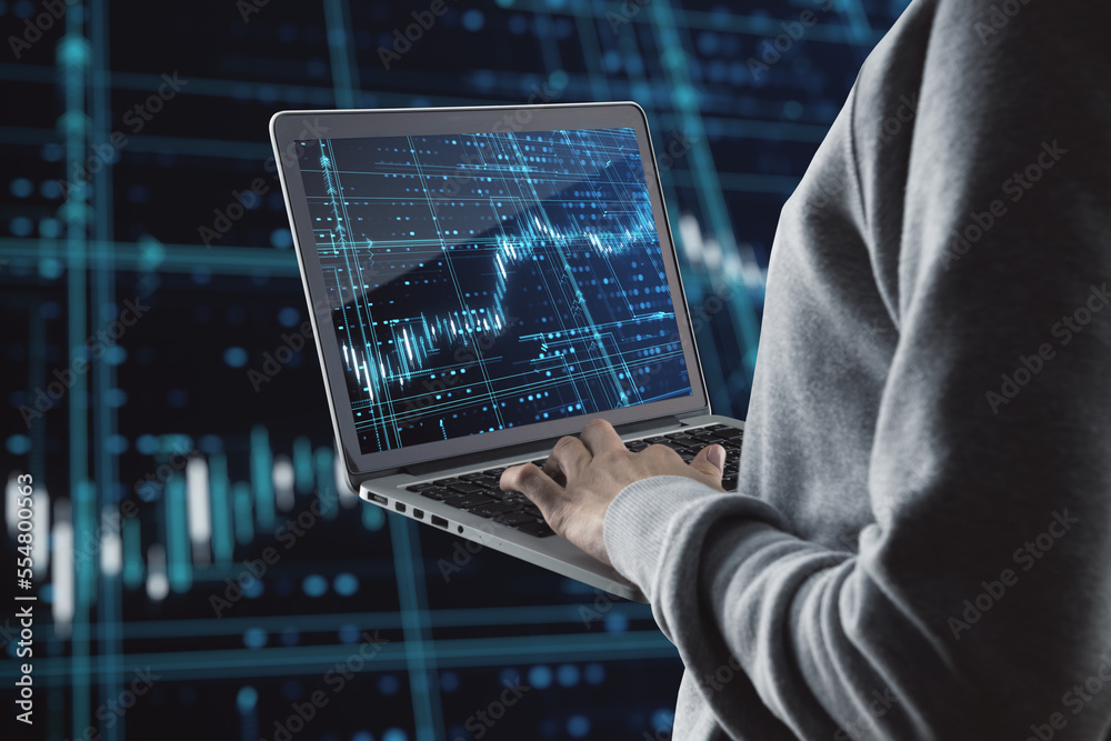 Aufkleber Close up of hand holding and using laptop computer with glowing forex index chart/graph on dark background. Trade, finance and market concept.