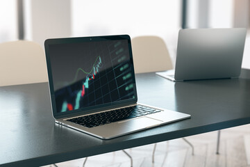 Close up of laptop computer with forex index chart/graph on screen, placed on desktop and blurry office background. Trade, finance and market concept. 3D Rendering.