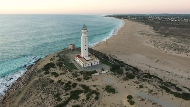 Reveal Drone shot of Trafalgar Lighthouse on the Costa de la Luz in Ca&ntilde;os de Meca, Cadiz Andalucia, Spain. Faro de Trafalgar beautiful evening with blue sea