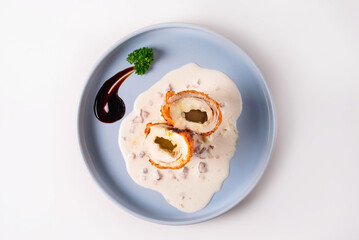 cordon bleu dish in sauce on a white background