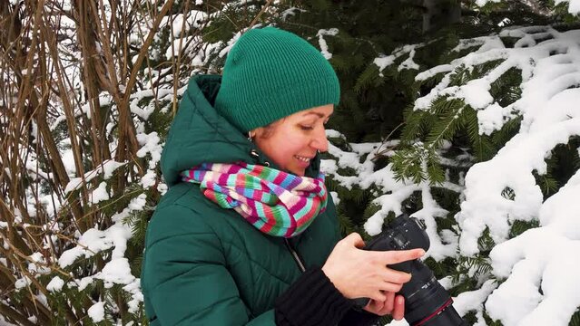 Portrait of a young woman with a camera in winter. The girl photographs the winter. Happy young woman with a camera in a snowy park.