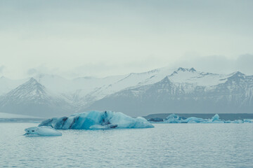 Blue icebergs floating near coast landscape photo. Beautiful nature scenery photography with mountain on background. Idyllic scene. High quality picture for wallpaper, travel blog, magazine, article