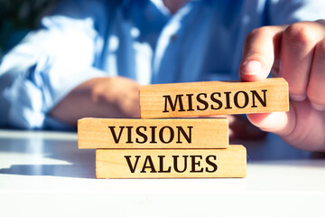 Closeup on businessman holding a wooden blocks with text MISSION, VISION, VALUES, business concept