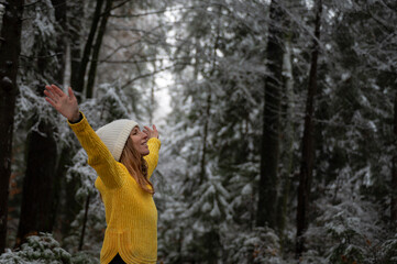 Young woman in yellow sweater enjoying life in winter forest