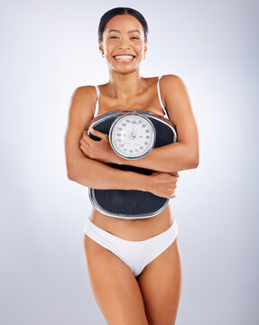 Portrait, black woman and scale for diet, weight loss and smile for healthy lifestyle, wellness and relax on grey studio background. African American female, weigh and health for body care or balance