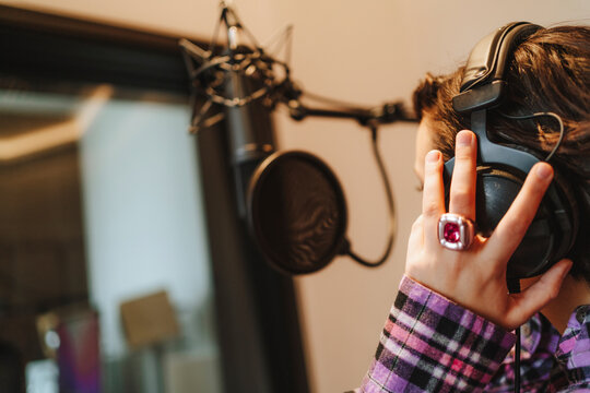 Hand of singer on headphones in studio