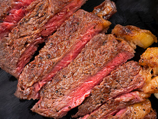 Sliced medium rare grilled Beef steak on wooden cutting board