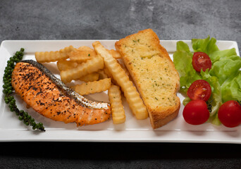 Fresh cooked delicious salmon steak with French fries and toast bread. 